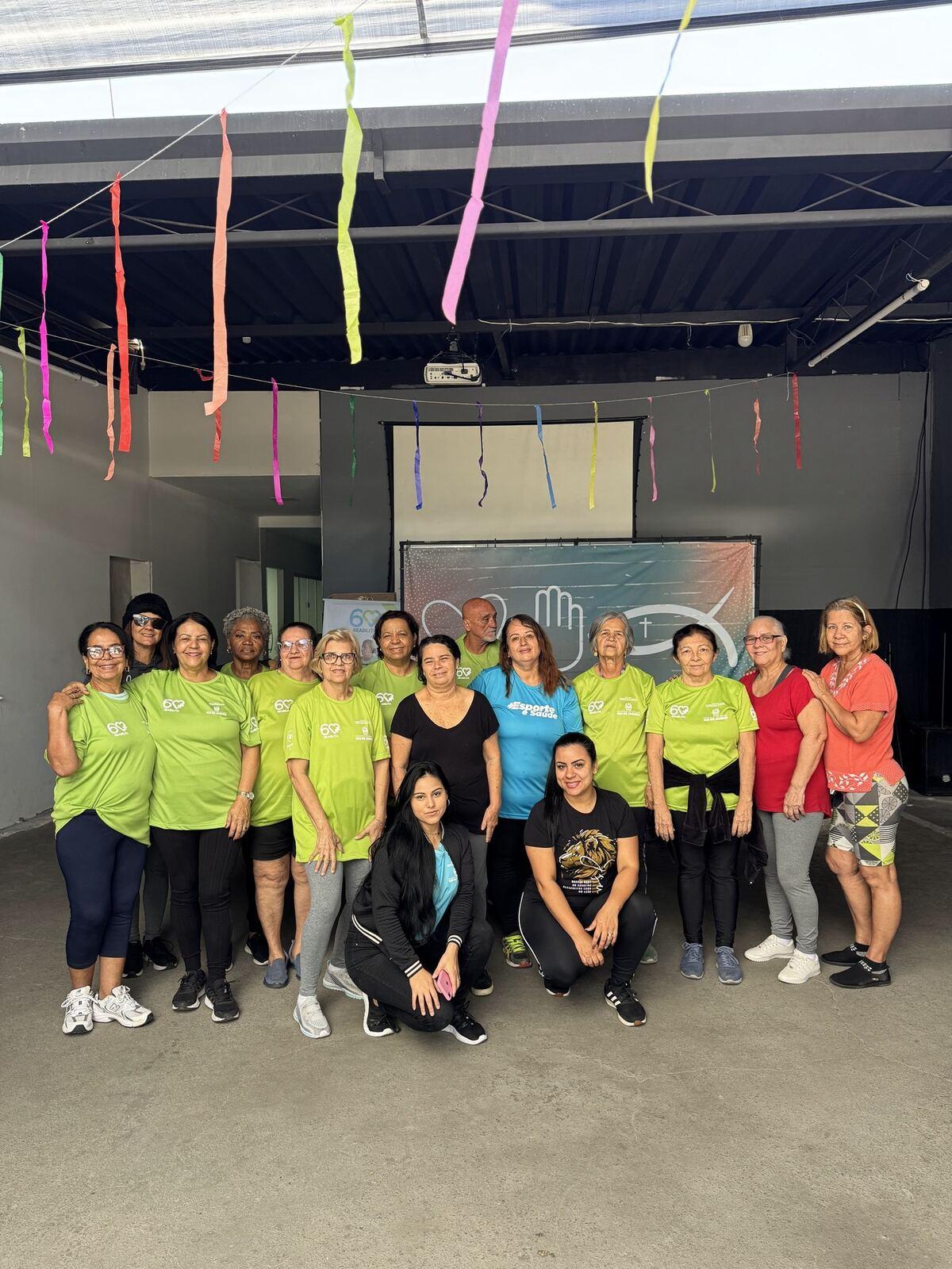 Turma reunida no pátio coberto do Instituto, de camiseta verde, sob bandeirinhas coloridas